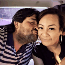 a man kisses a woman on the cheek in a striped shirt