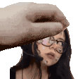 a woman wearing glasses and a headset is being slapped by a hand .