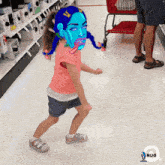 a girl with a blue face is dancing in a store with a rug logo in the corner