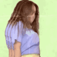 a woman in a blue shirt and yellow shorts is dancing .