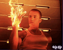 a man in a white tank top is holding a fire hand