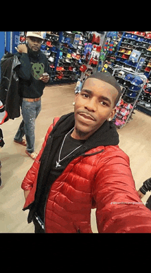 a man in a red jacket is taking a selfie in a shoe store