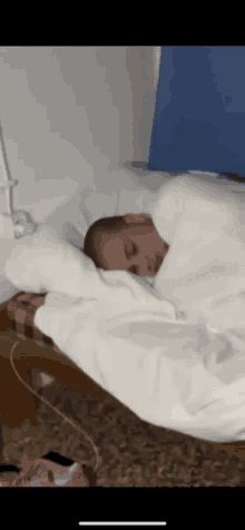 a man sleeping on a bed with a white blanket