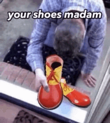 a man is holding a pair of red and yellow clown shoes in front of a door .