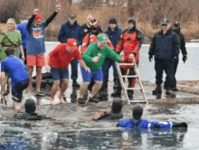 a group of people are standing in a body of water and one of them is wearing a shirt that says ' toronto '