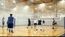 a group of people are playing volleyball in a gym with a net that says ' volleyball ' on it