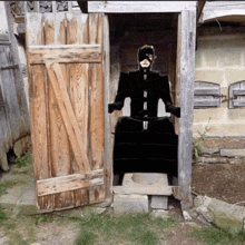 a person in a black mask is sitting in a wooden outhouse