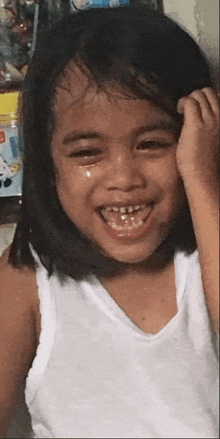 a little girl is crying and smiling with a tear coming out of her eye .