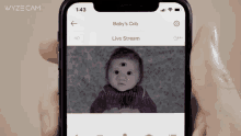 a person is holding a phone that shows a baby 's crib live stream