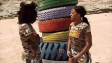 two girls standing next to a stack of tires with one wearing a shirt with the number 10 on it