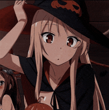 a girl with long blonde hair wearing a witch hat with a pumpkin on it