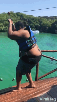 a man wearing a life jacket is standing on a dock overlooking a body of water with viralhog written on the bottom