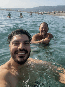 two men are swimming in the ocean and smiling for the camera