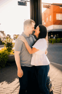 a man and a woman are hugging and looking at each other on a sidewalk