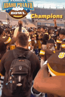 a group of football players are celebrating in front of a sign that says ' idaho potato bowl champions '