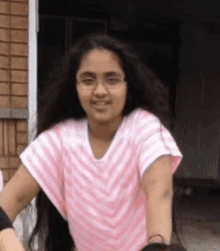 a young girl with long hair and glasses is standing in front of a door .