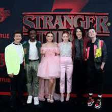 a group of people standing next to each other in front of a sign that says stranger things .