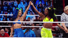 a couple of women are standing in a wrestling ring giving each other a high five .