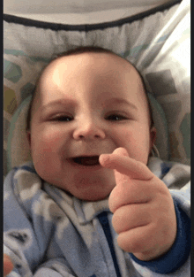 a baby in a blue blanket is giving a thumbs up sign