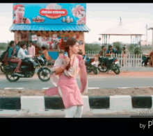 a woman in a pink dress is walking down the street in front of a store that sells cream cookies