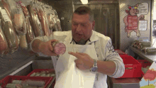 a man in an apron holds a piece of meat in front of a sign that says " die größte europäische Wurst "