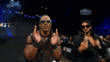 three men wearing sunglasses are standing in front of a sign that says aew on it