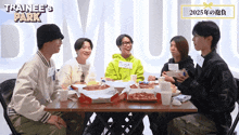 a group of young men are sitting at a table with trainee 's park written on the wall behind them