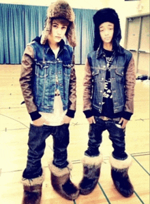 a boy wearing a denim jacket and a fur hat stands next to another boy wearing fur boots