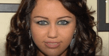 a close up of a woman 's face with blue eyes and curly hair