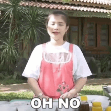 a woman in an apron is standing in front of a table with bowls of food and a sign that says oh no .