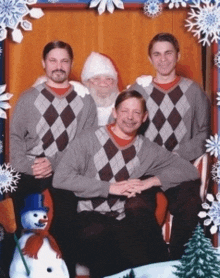 a group of men pose for a picture with santa claus and a snowman