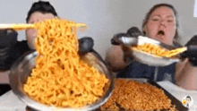 a man and a woman are eating ramen noodles with chopsticks and spoons .