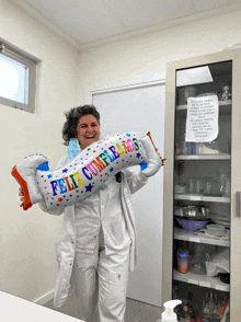 a woman in a lab coat holding a balloon that says feliz cumpleanos