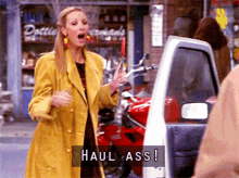 a woman in a yellow coat is standing in front of a red motorcycle and says haul ass