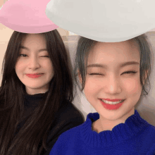 two girls are posing for a picture with a pink and white balloon on their head