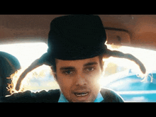 a man wearing a top hat and a wig is driving a car .