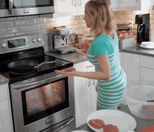 a woman in a blue and white striped dress is standing in front of a stove that says ' viking ' on the front