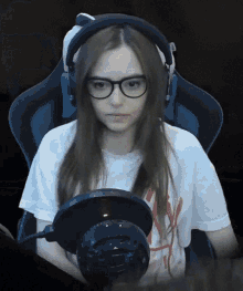 a girl wearing glasses and headphones is sitting in a gaming chair