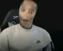 a man wearing a white nike sweater is making a funny face .