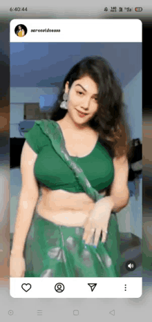 a woman in a green crop top and a green saree is on a phone screen