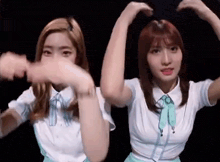 two girls are making a heart shape with their hands while dancing .
