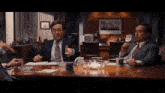 a group of men are sitting around a table with a cup that says ' a.m. ' on it