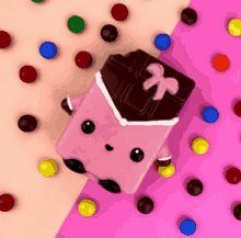 a pink chocolate bar with a bow on it is surrounded by m & m 's