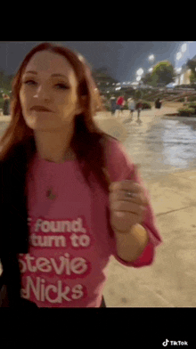 a woman is wearing a pink shirt that says " found turn to stevie nicks "