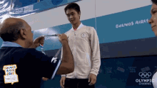 a man is giving a medal to a young man in front of a wall that says buenos aires on it