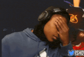 a woman wearing headphones covering her face with her hand