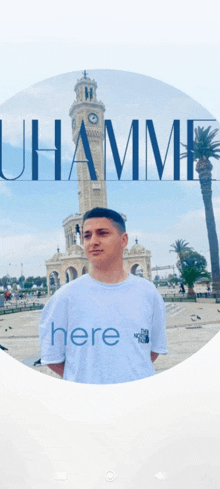 a man wearing a white shirt that says here is standing in front of a building