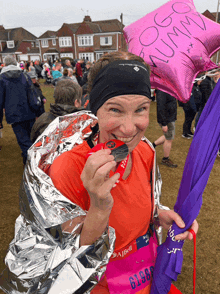 a woman holding a pink balloon that says mum