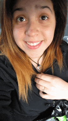 a woman wearing a necklace and a ring is smiling for the camera