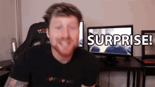 a man sitting in front of a computer with the words surprise written on the screen